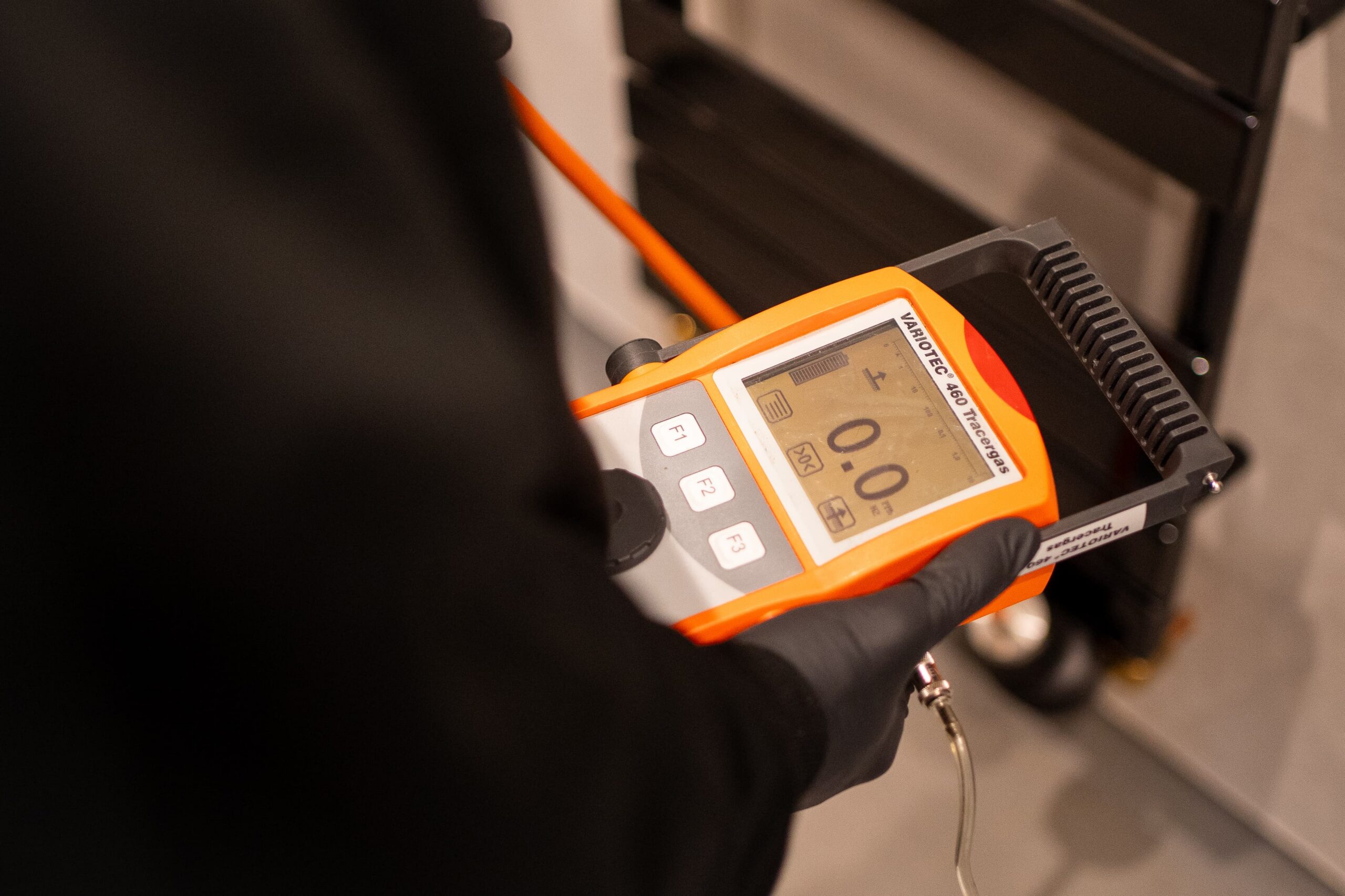 Disaster Care technician deploying tracer gas detection equipment to locate leak beneath floor 